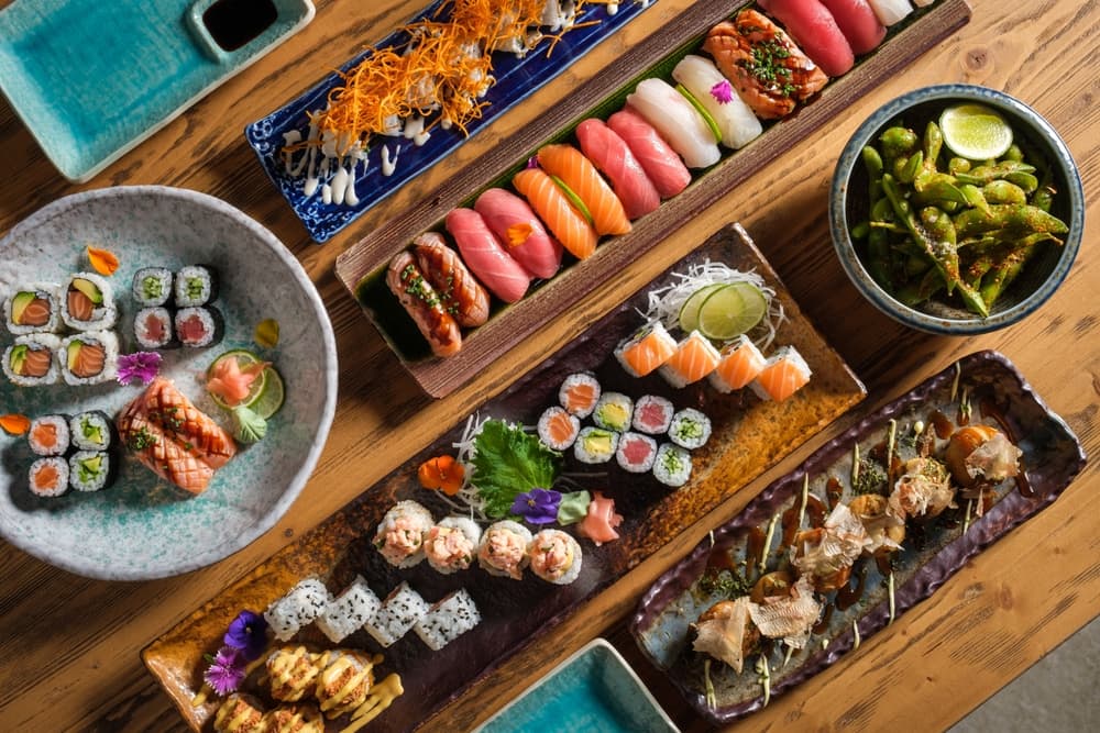 Top view of delicious sushi and rolls with fresh fish and green peas served on wooden table in light cafe