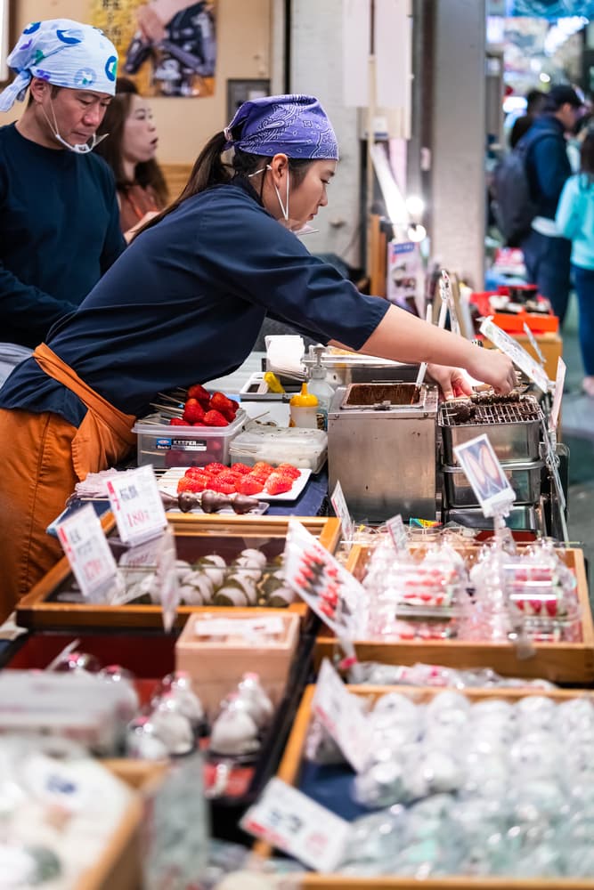 People serving at Nishiki market shops food vendor selling rice cake mochi sweets
