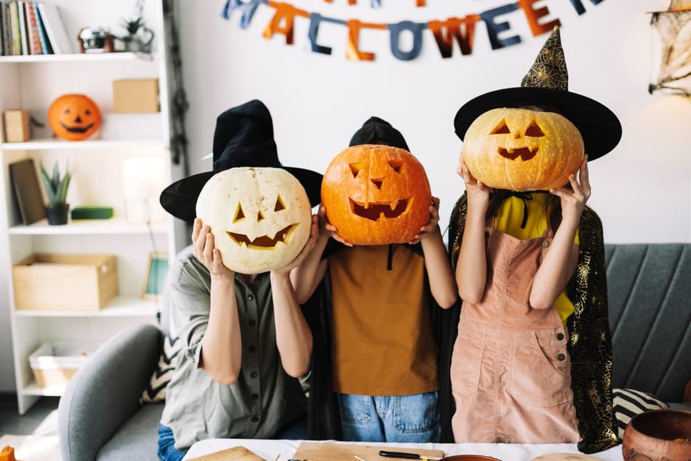 Family in witch hats and carved pumpkins, having fun at home for halloween