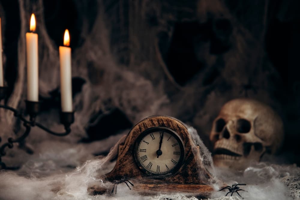 Dark Halloween background with old clock, candles and spider web