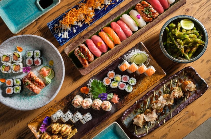 Top view of delicious sushi and rolls with fresh fish and green peas served on wooden table in light cafe